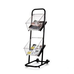 A black and clear PETG acrylic publication stand with two tiers and castor wheels with magazines inside.