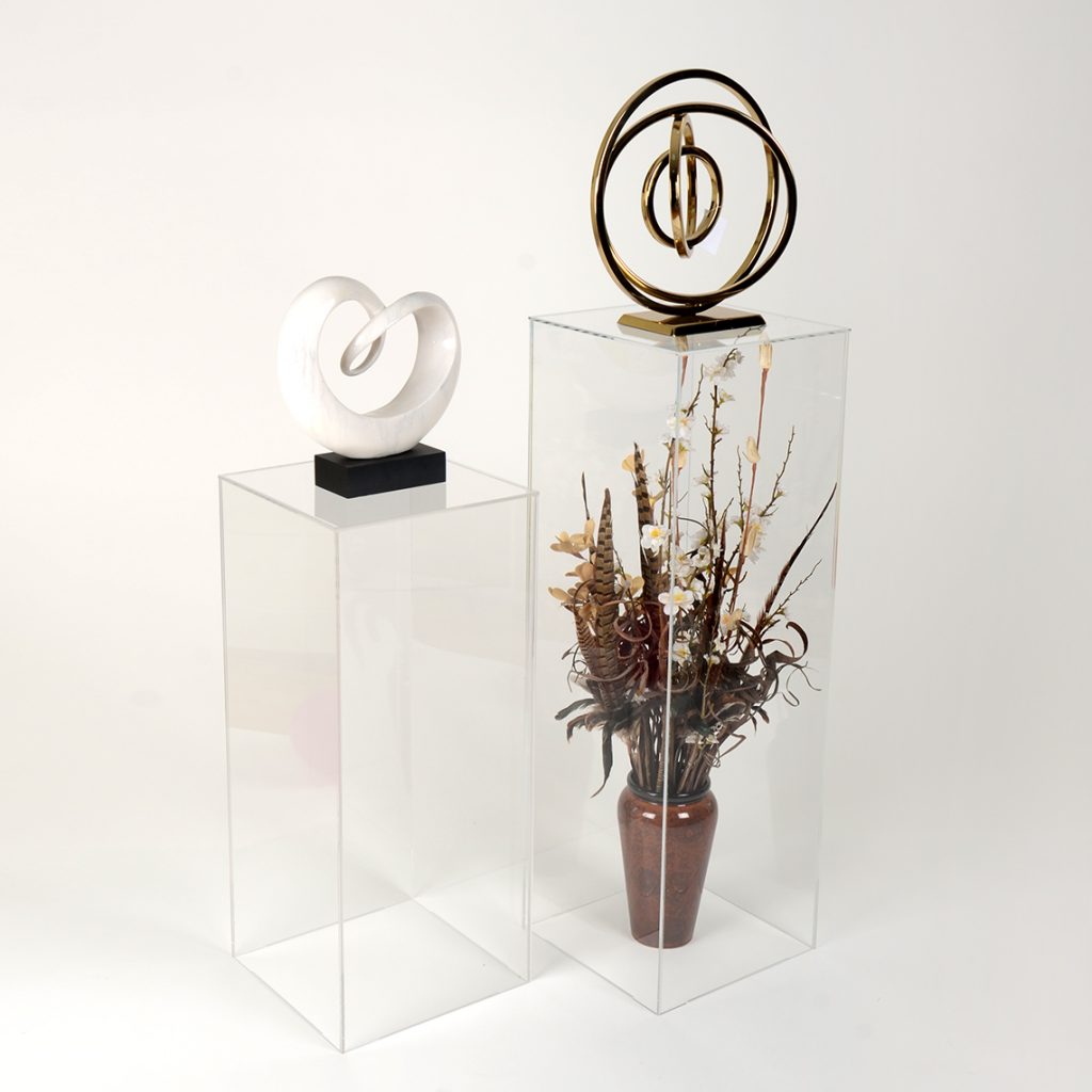 Two Clear Acrylic Display Plinth Pedestals With Sculptures On Display.