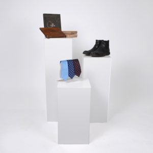Three White Display Plinths With Mens Clothing On Display.