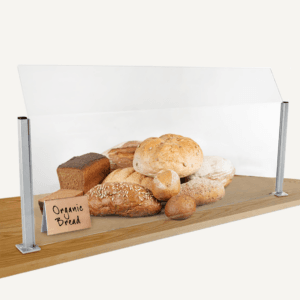 A counter sneeze guard with bread behind it and a wooden sign.