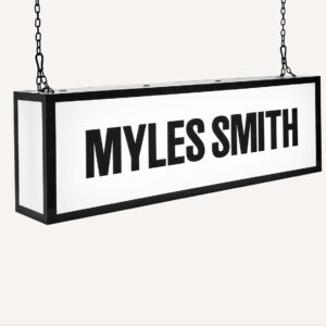 A ceiling hanging illuminated sign with "Myles Smith" on the front.