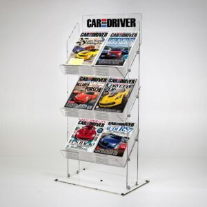A clear acrylic magazine and newspaper display stand with magazines and a logo.