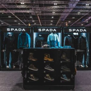A front facing picture of a Feridax Spada exhibition display, showcasing clothing and shoes under lighting.
