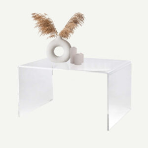 clear acrylic coffee table with a vase displaying grasses and three candles on top.