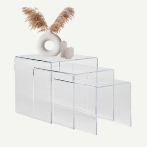 A picture of a nest of three clear acrylic tables with a vase and three candles on the tables.