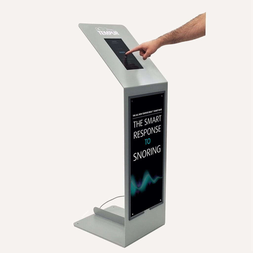 A hand reaching in to interact with the Tempur digital silent salesman touch screen.
