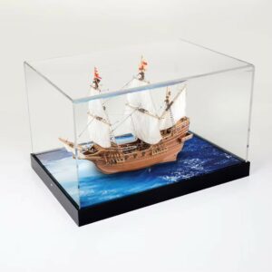 A model sailing ship inside a custom display case with a sea like printed base.