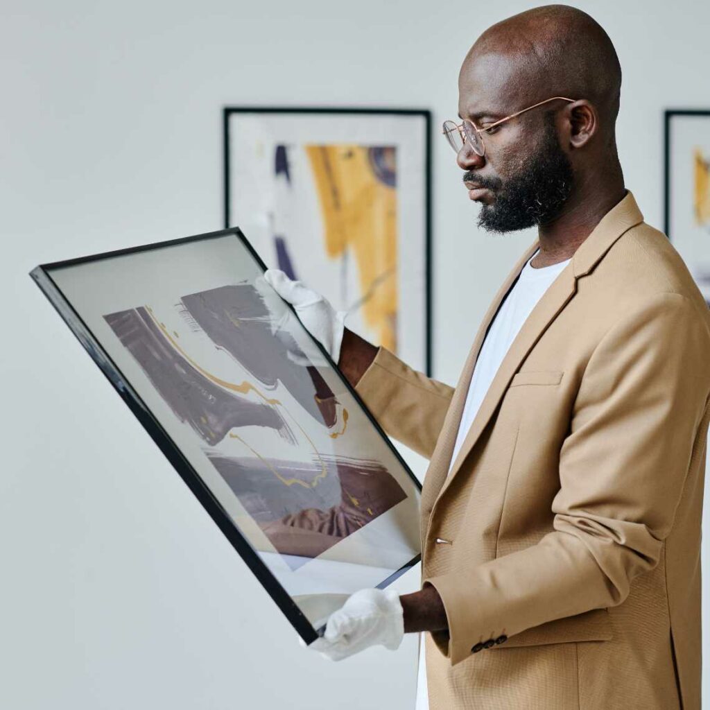 A man holding a frame in an art gallery.