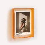 A bright orange acrylic frame with a print inside.