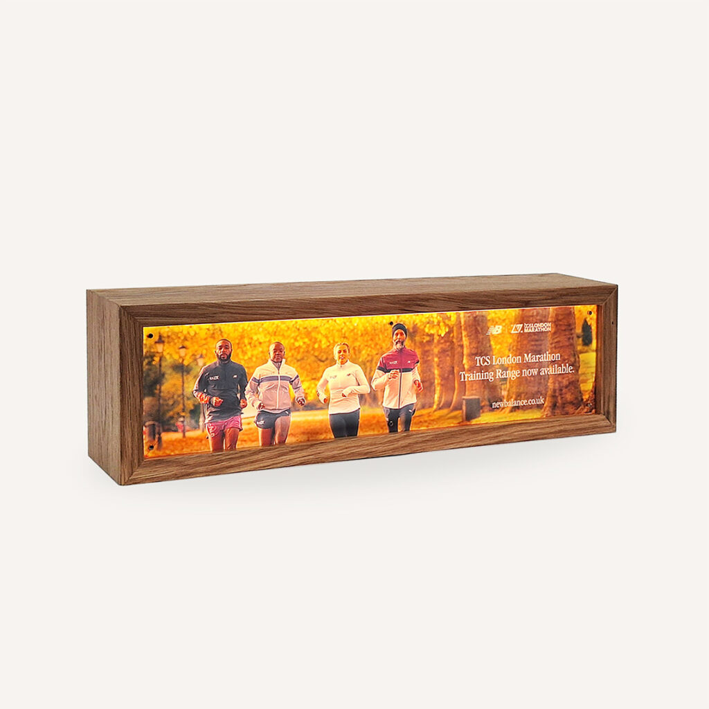 Illuminated Wooden Lightbox with Custom branding for New Balance facing the left. Shown in a light room.