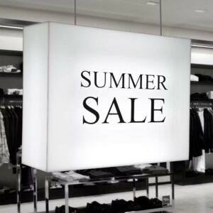 A ceiling hanging illuminated sign in a clothes shop with "summer sale" printed on it.
