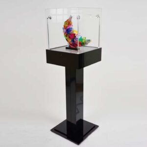 A black plinth pedestal with a protective cover and a decorative ornament on display.