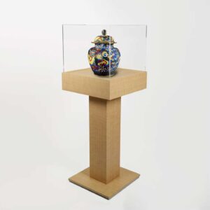 A wooden plinth pedestal with a protective cover and vase on display.