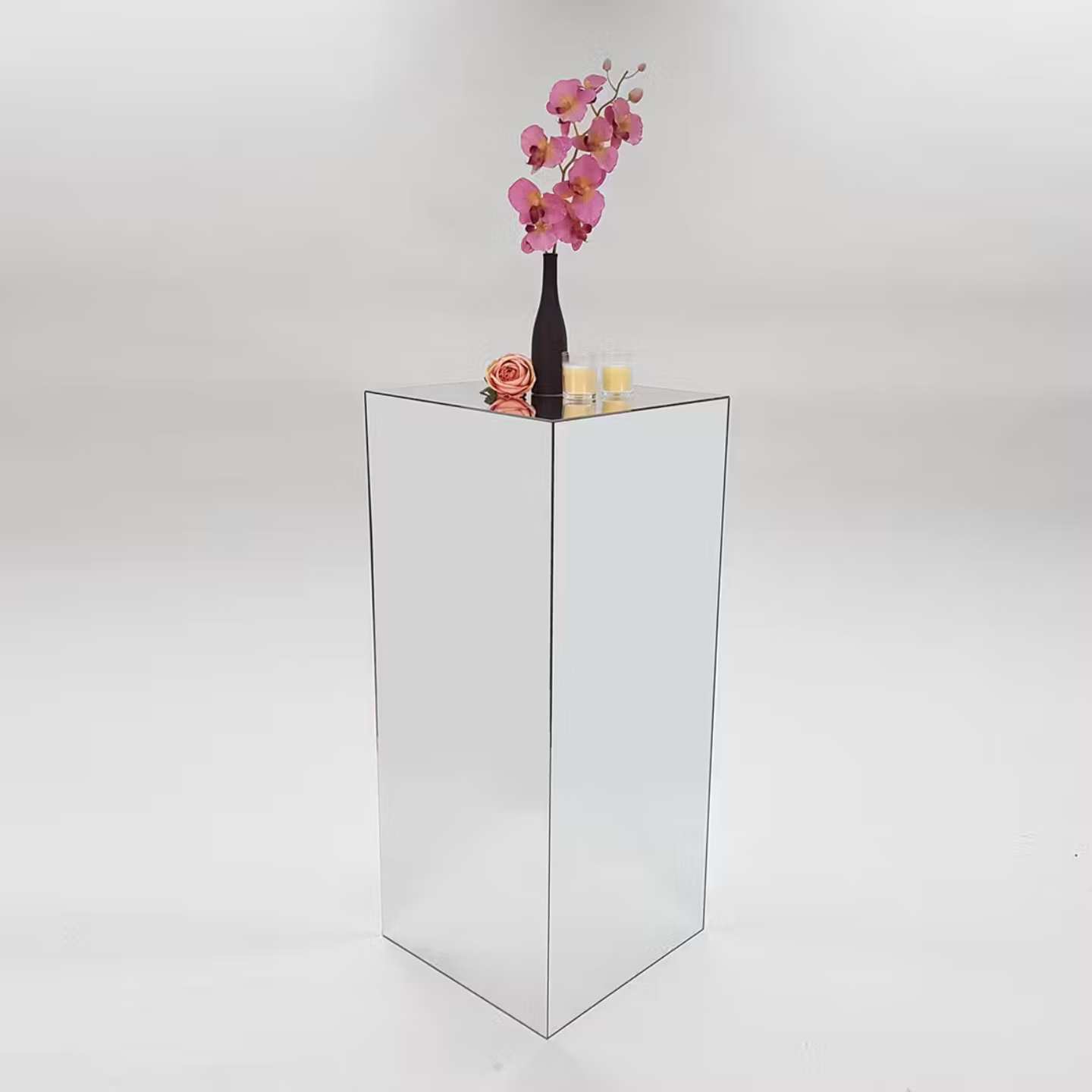 A white plinth with a decorative flower and vase on top.