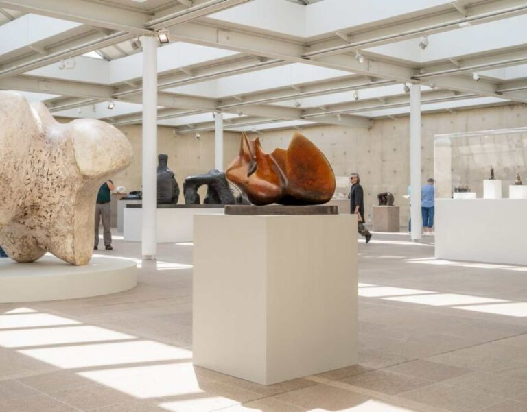 A white plinth with a sculpture on top in a gallery.